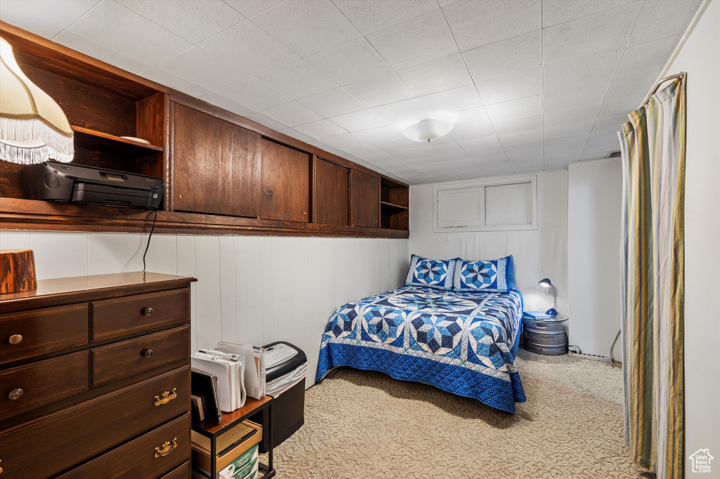 Carpeted bedroom featuring wooden walls