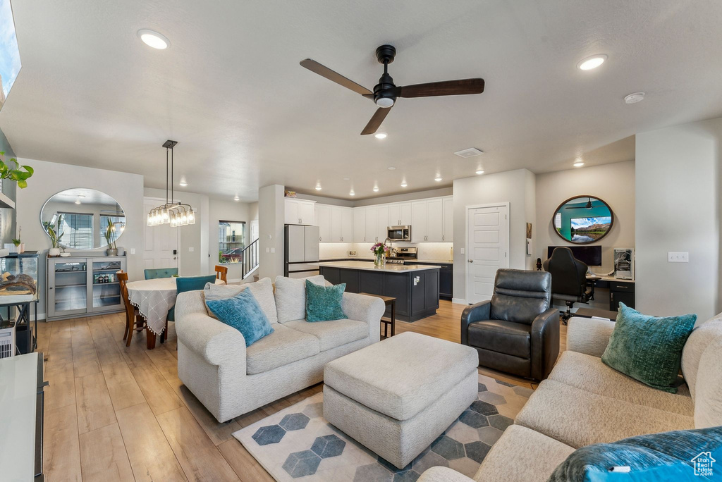 Living room featuring recessed lighting, visible vents, ceiling fan with notable chandelier, and light wood-type flooring