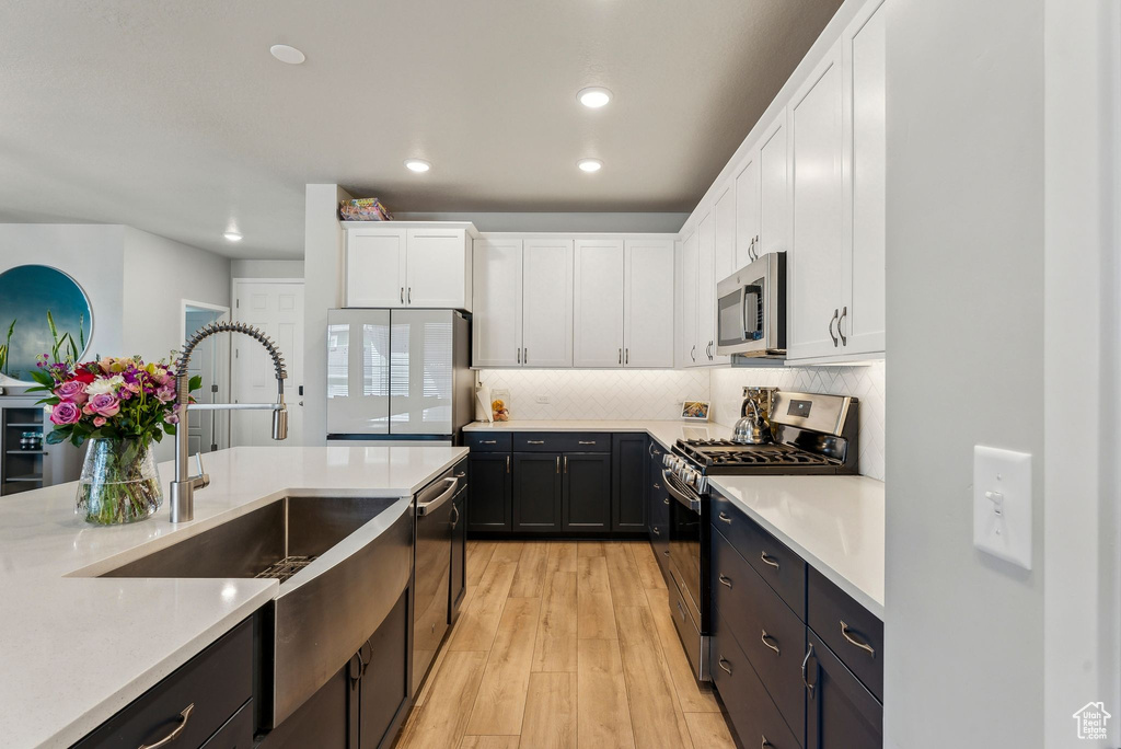 Kitchen with light countertops, stainless steel appliances, and white cabinetry