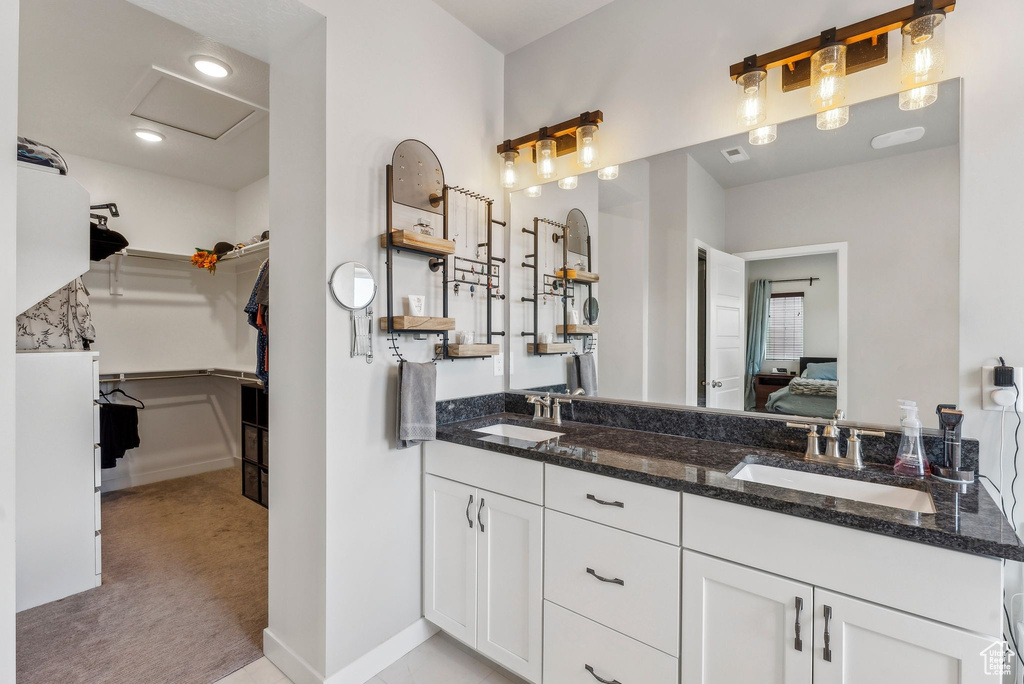 Bathroom with double vanity, a spacious closet, a sink, and ensuite bathroom