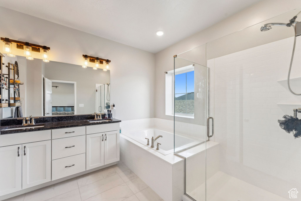 Bathroom featuring double vanity, a shower stall, a sink, and a garden tub