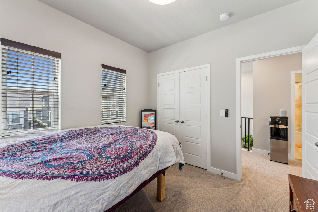 Bedroom featuring baseboards, a closet, and light colored carpet