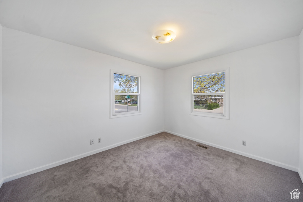 Unfurnished room with visible vents, carpet flooring, baseboards, and a healthy amount of sunlight