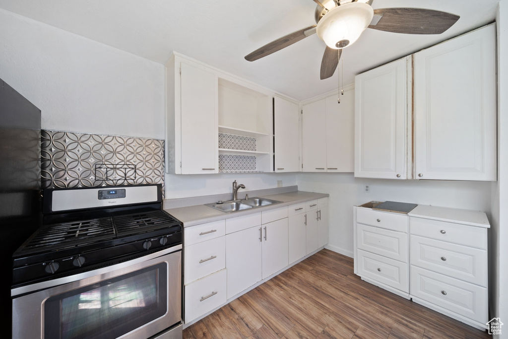 Kitchen featuring open shelves, gas stove, light countertops, a sink, and white cabinetry