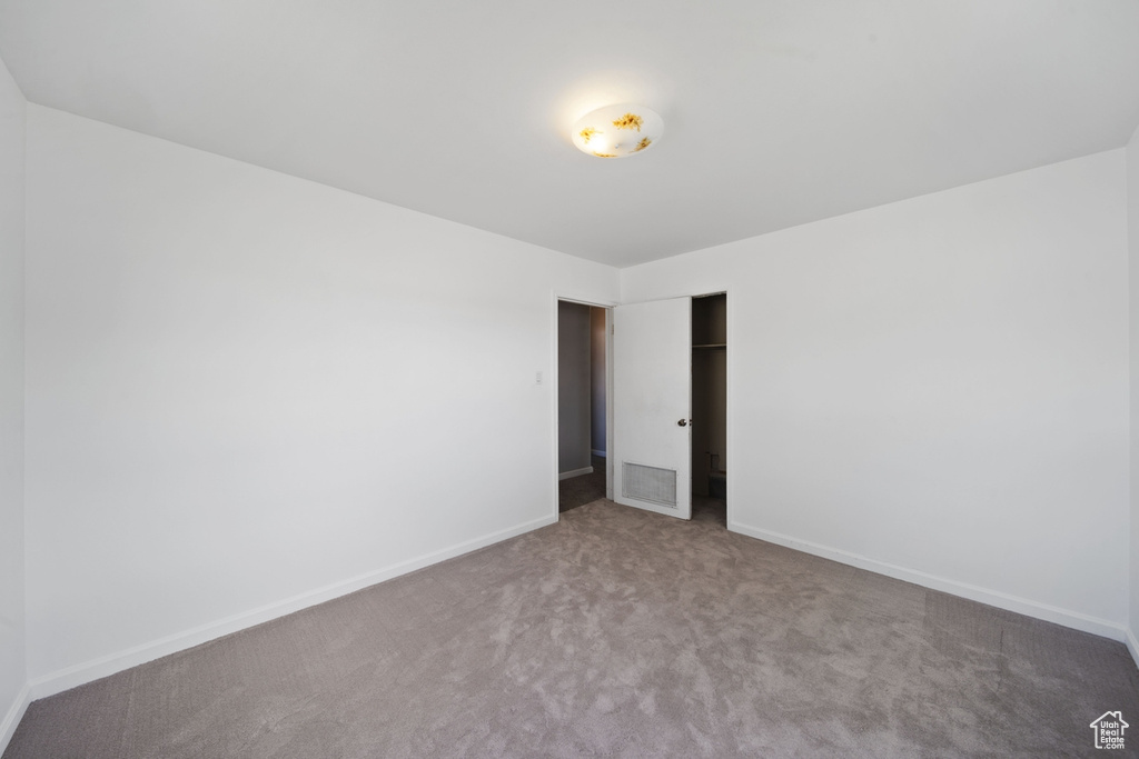 Carpeted empty room with baseboards and visible vents