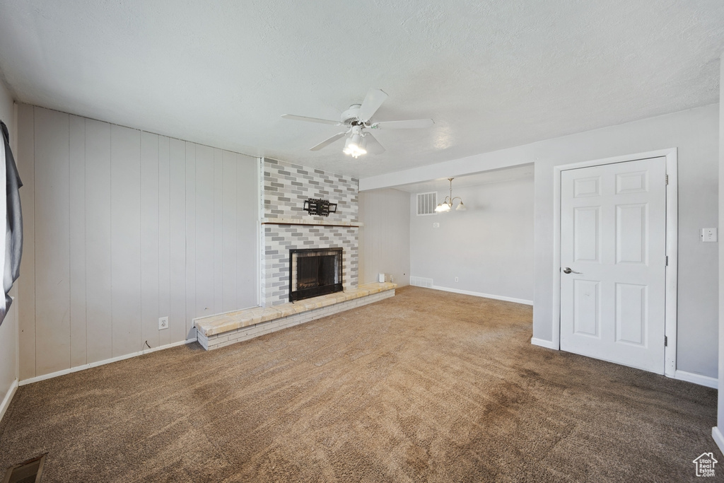 Unfurnished living room featuring carpet floors, baseboards, ceiling fan, and a fireplace