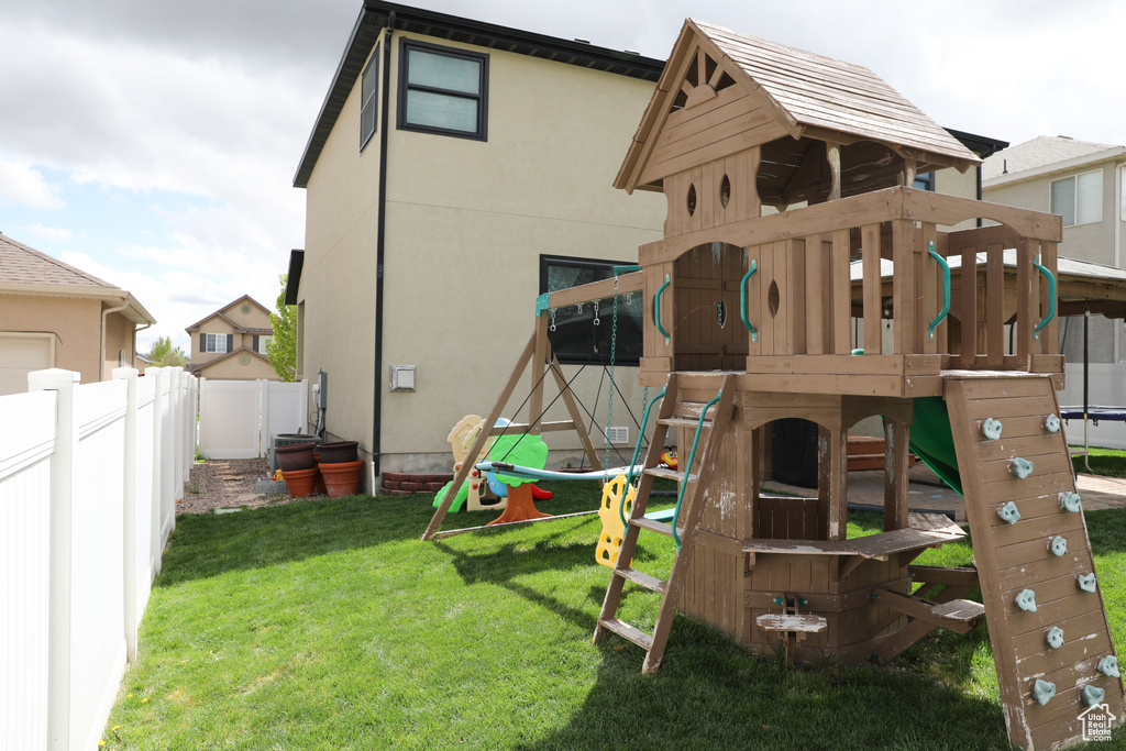 View of play area with a lawn and fence