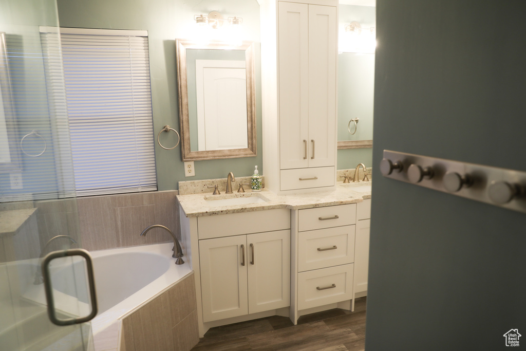 Full bath featuring wood finished floors, a garden tub, and vanity