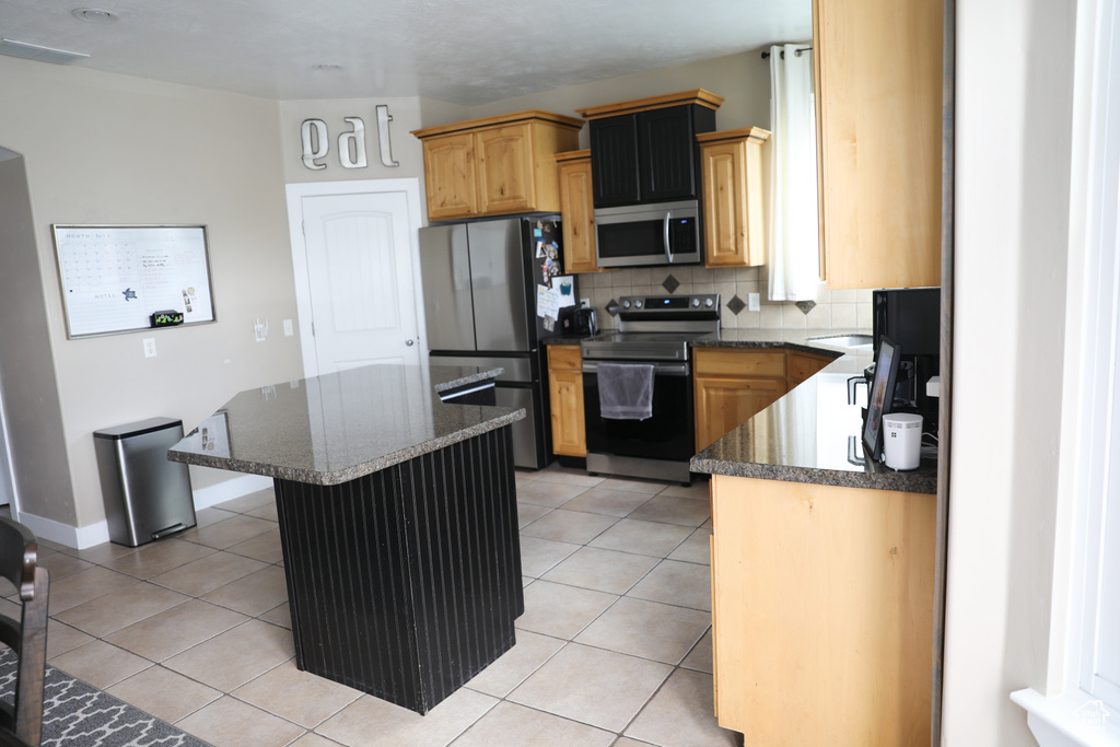 Kitchen with visible vents, a kitchen island, dark stone countertops, backsplash, and stainless steel appliances