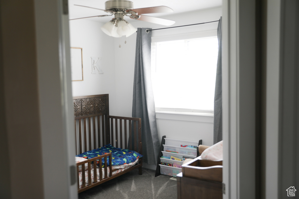 Carpeted bedroom with a nursery area and a ceiling fan
