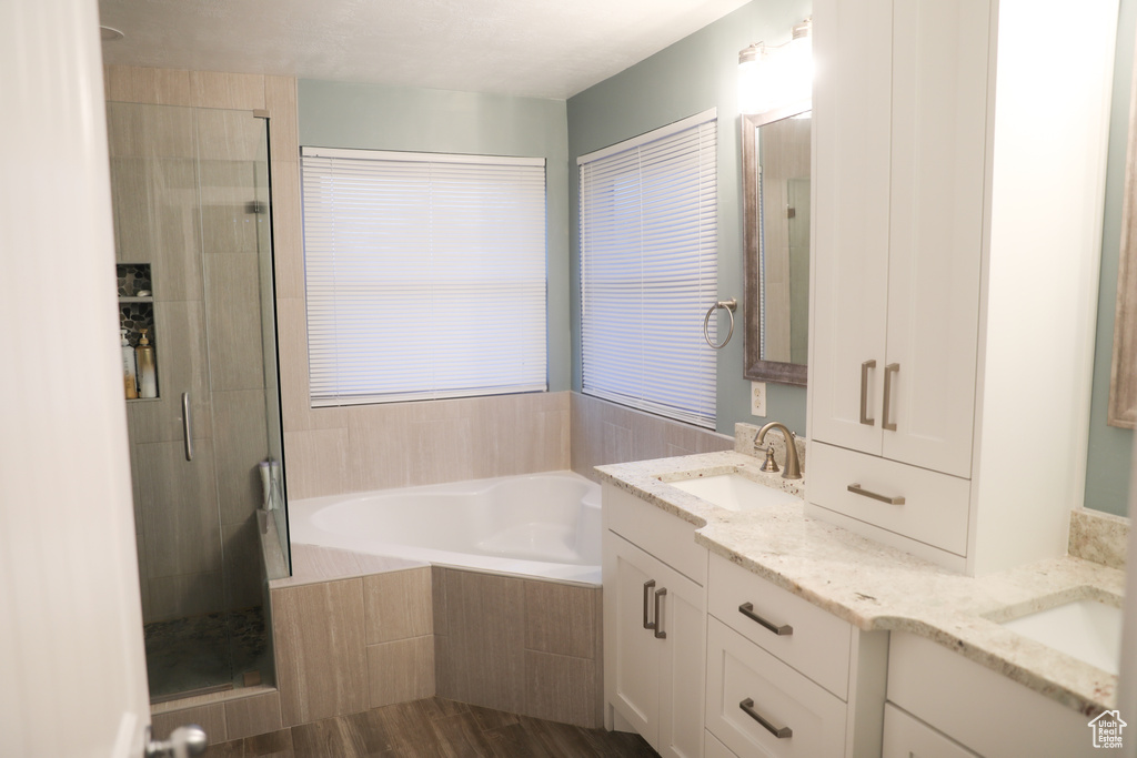 Full bathroom featuring double vanity, a shower stall, a sink, and a garden tub