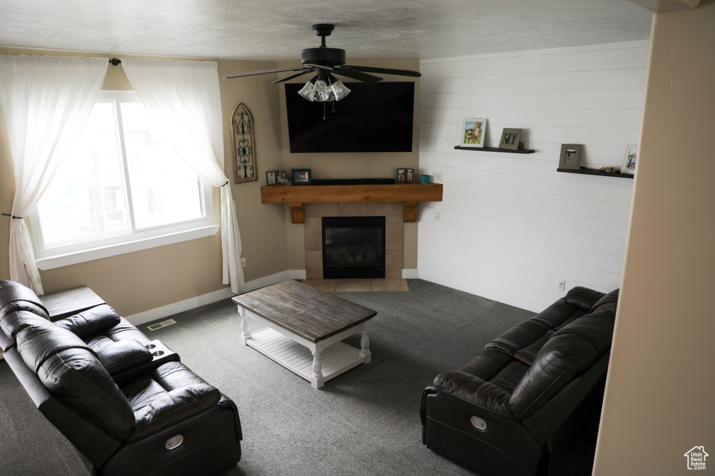 Living room with a ceiling fan, visible vents, a fireplace, carpet floors, and baseboards