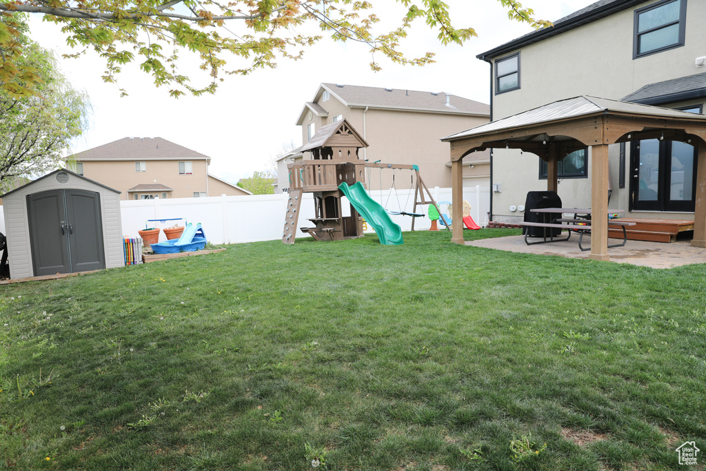 View of yard featuring a patio area, a gazebo, a fenced backyard, a playground, and a shed