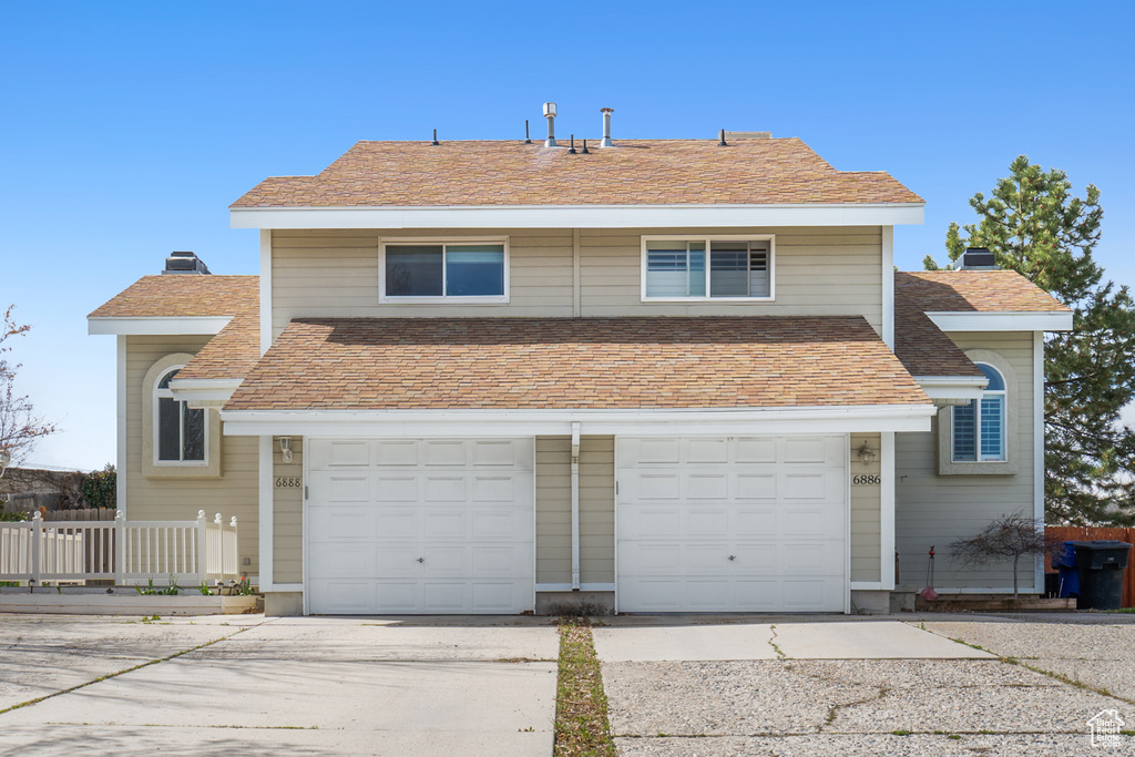 Traditional-style house with an attached garage, fence, driveway, and a chimney