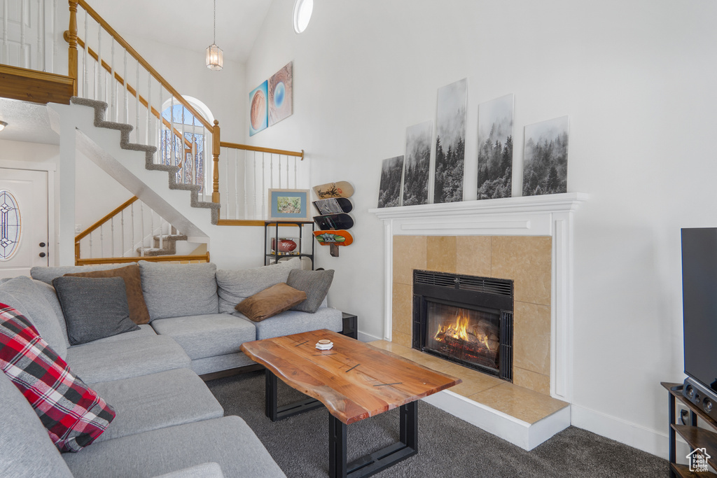 Carpeted living area featuring stairs, a high ceiling, baseboards, and a fireplace