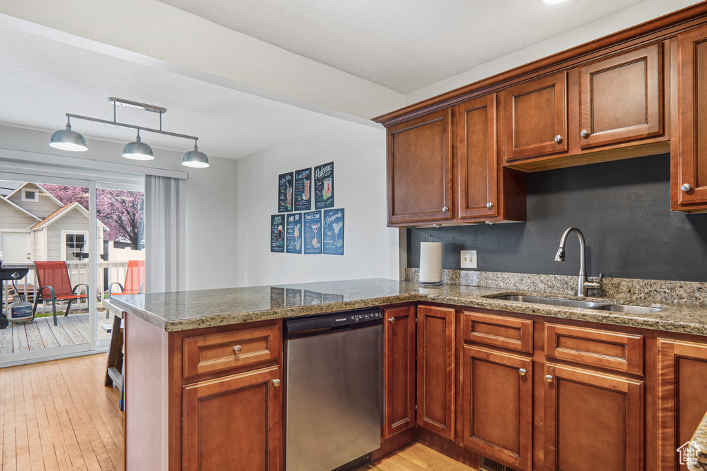 Kitchen with light wood-type flooring, dishwasher, a sink, light stone counters, and a peninsula