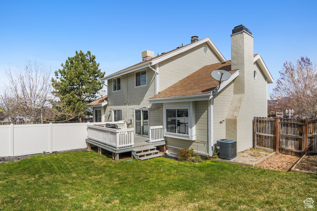 Rear view of property with a fenced backyard, central air condition unit, a yard, and a chimney