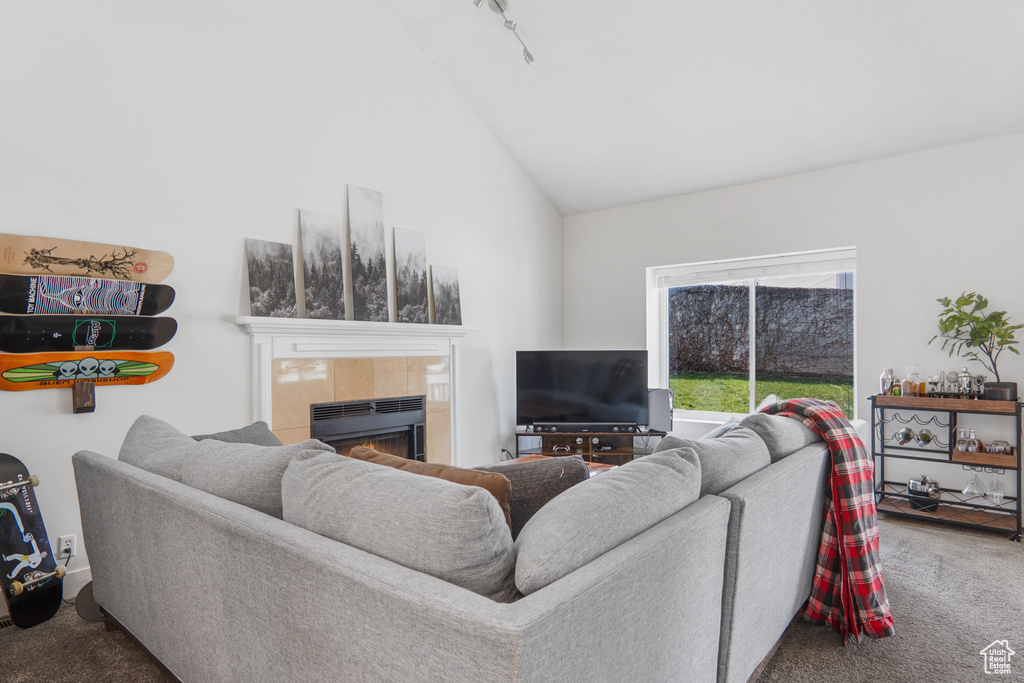 Carpeted living area with high vaulted ceiling and a fireplace