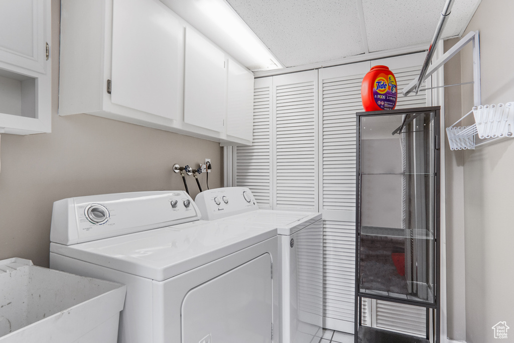 Washroom with cabinet space, tile patterned floors, a sink, and washer and clothes dryer