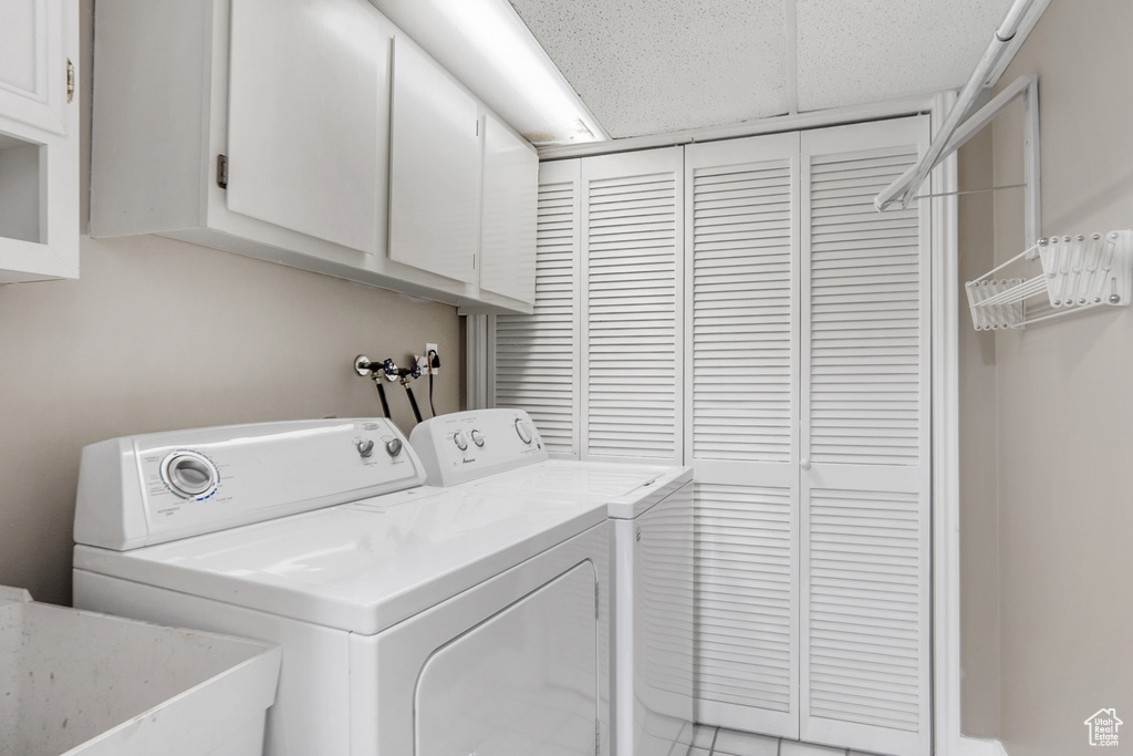 Clothes washing area featuring cabinet space, a sink, and washer and dryer