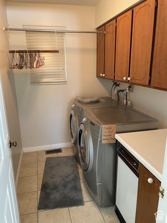 Clothes washing area with visible vents, cabinet space, baseboards, light tile patterned flooring, and washer and clothes dryer