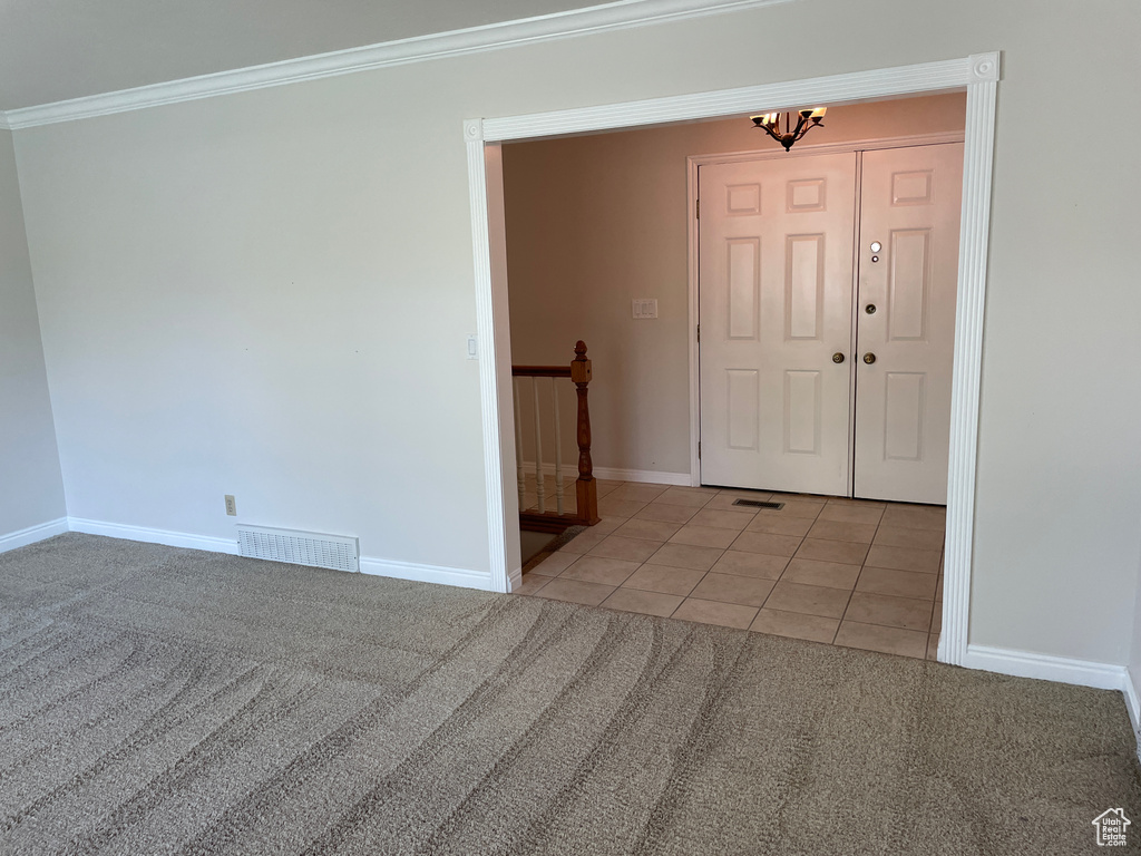 Empty room with an inviting chandelier, baseboards, light tile patterned floors, visible vents, and ornamental molding