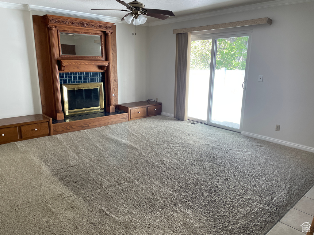 Unfurnished living room featuring ceiling fan, ornamental molding, baseboards, and a fireplace
