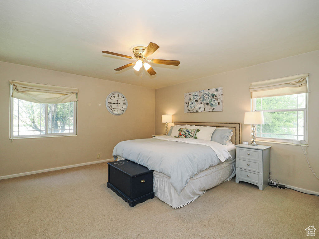 Bedroom with baseboards, multiple windows, light carpet, and ceiling fan