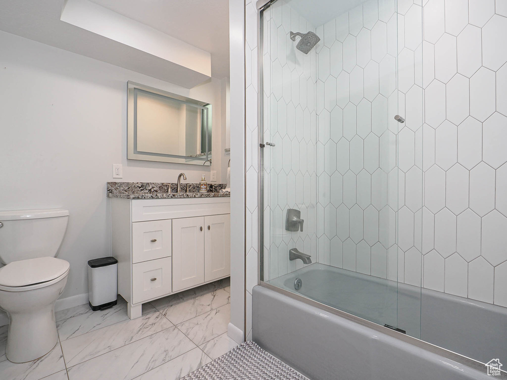 Bathroom with vanity, toilet, marble finish floor, baseboards, and shower / washtub combination