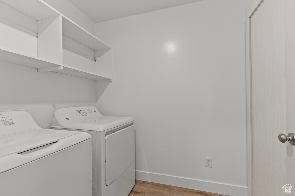 Laundry room with washing machine and clothes dryer, laundry area, baseboards, and light wood-style flooring
