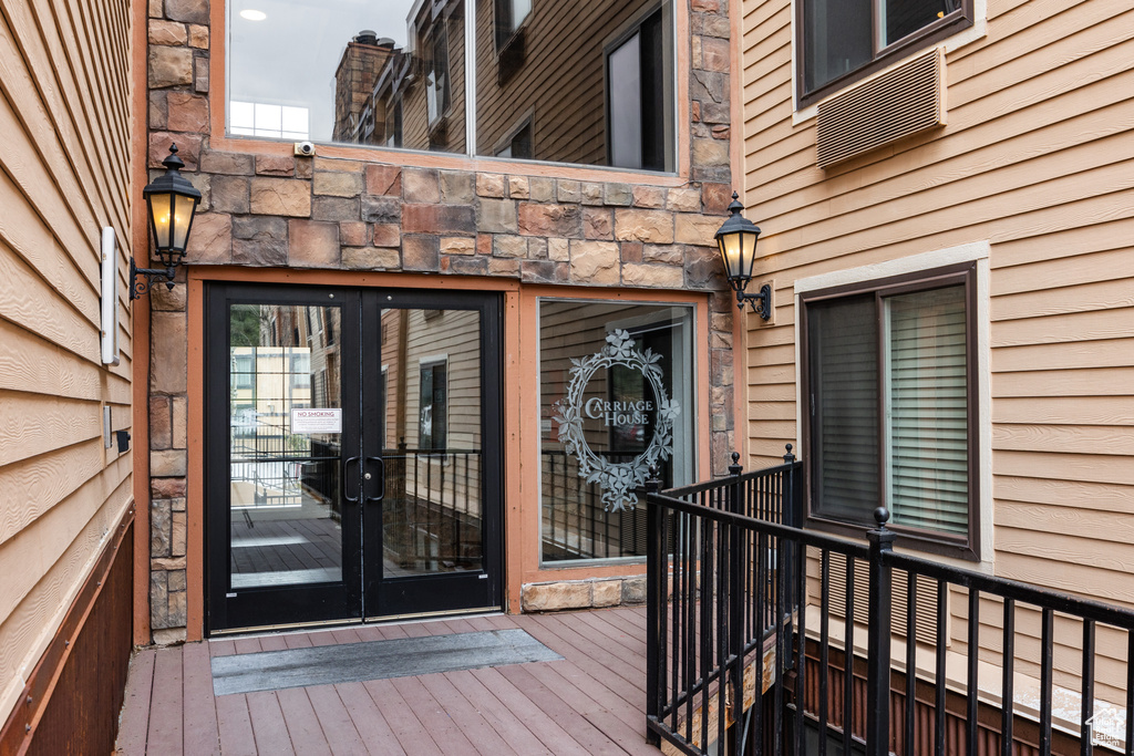 Doorway to property with french doors, stone siding, and a deck