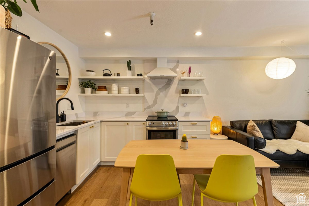 Kitchen featuring open shelves, a sink, light countertops, stainless steel appliances, and extractor fan