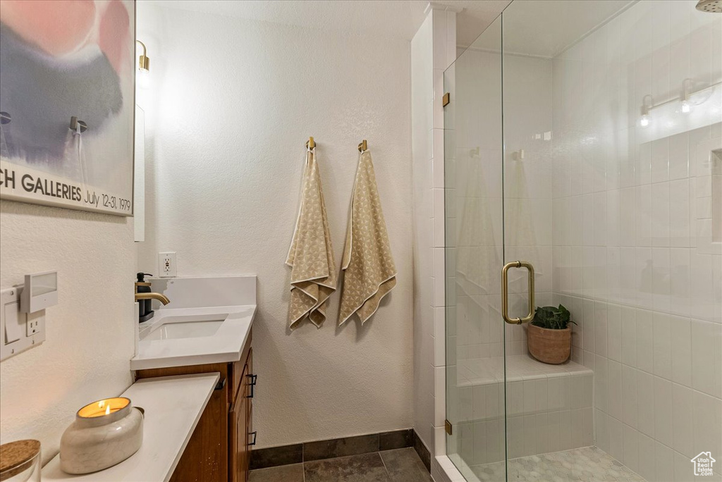 Full bath with baseboards, a shower stall, and vanity