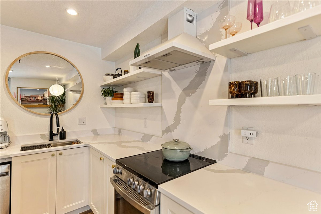 Kitchen with white cabinets, open shelves, a sink, stainless steel appliances, and island exhaust hood
