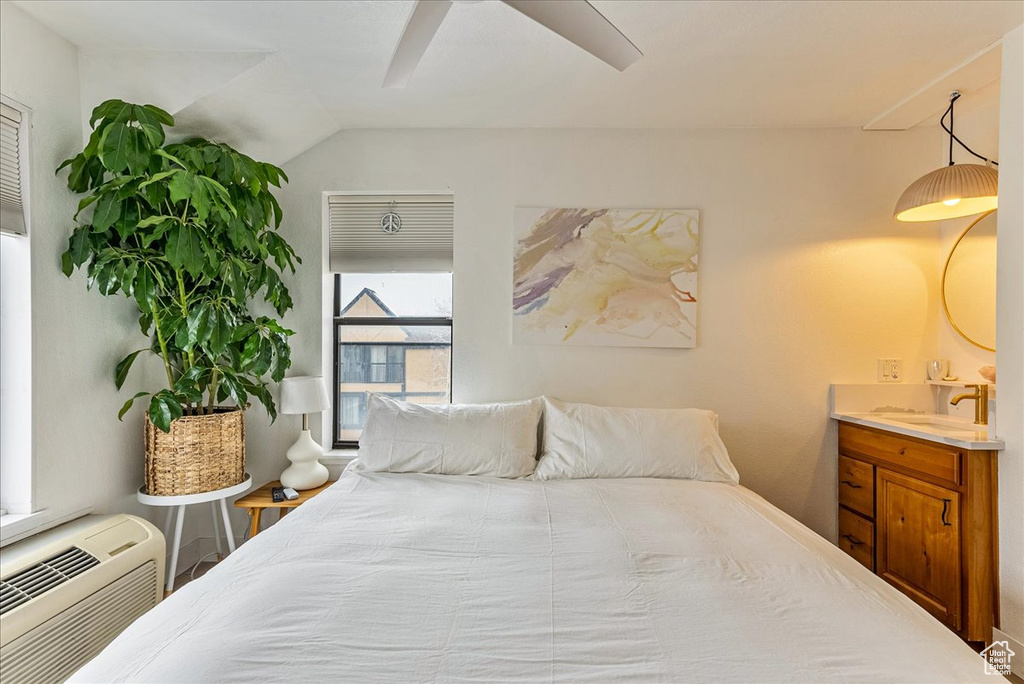 Bedroom featuring a sink, ceiling fan, a wall mounted air conditioner, and lofted ceiling