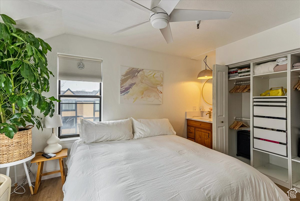 Bedroom with ceiling fan, ensuite bath, wood finished floors, lofted ceiling, and a closet