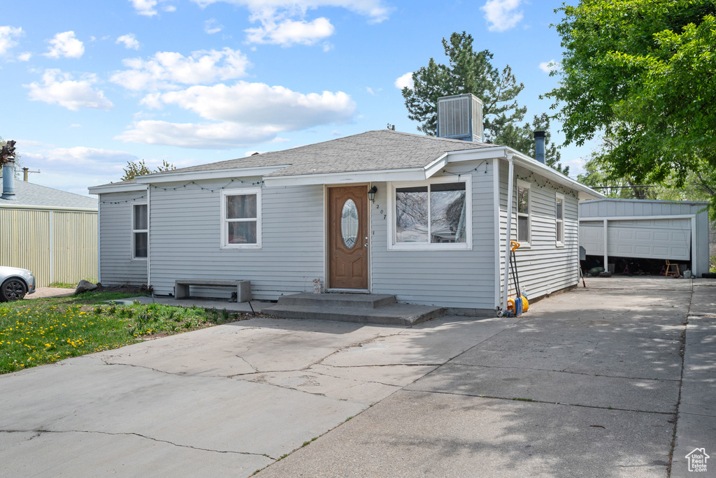 View of front of house with central AC unit and an outbuilding