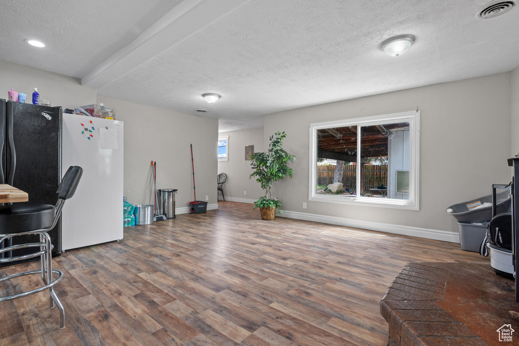 Interior space featuring baseboards, a textured ceiling, visible vents, and wood finished floors