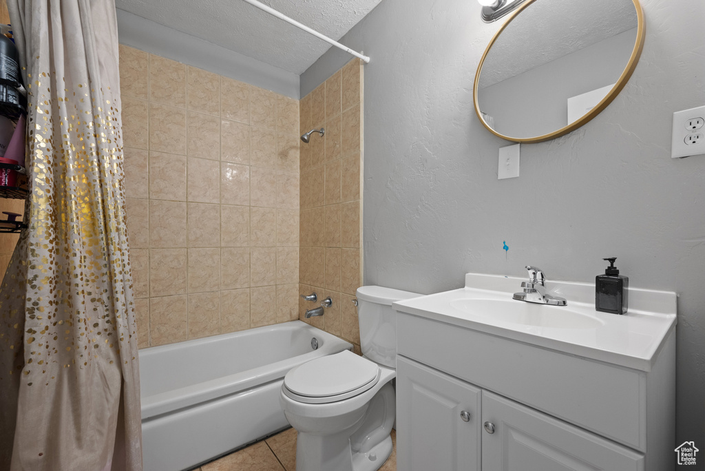 Bathroom featuring toilet, shower / bath combination with curtain, tile patterned flooring, and vanity