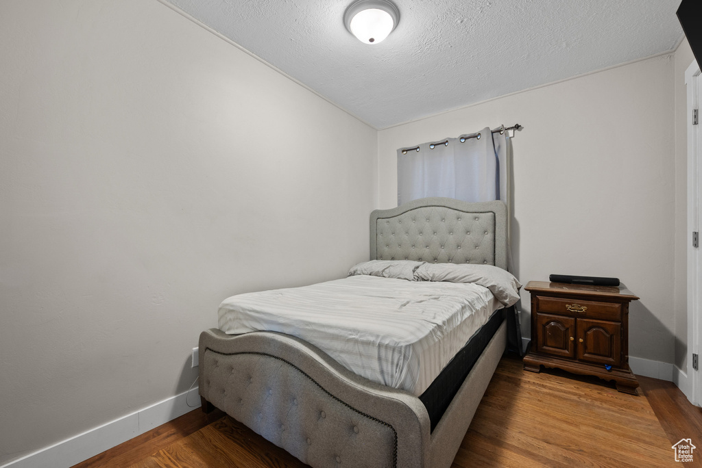 Bedroom featuring baseboards, a textured ceiling, and wood finished floors
