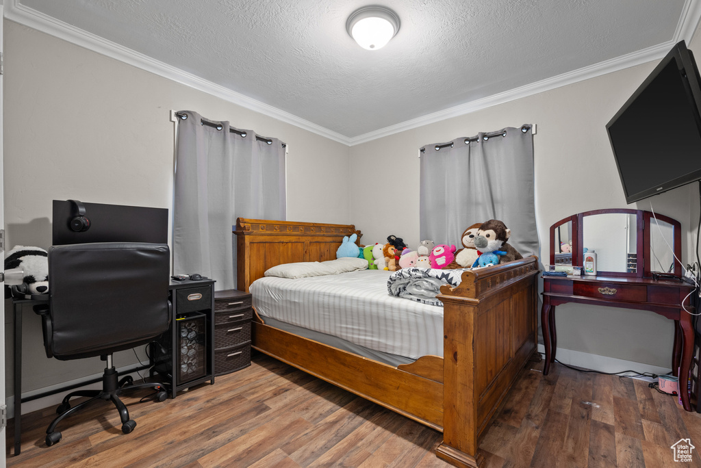 Bedroom featuring crown molding, a textured ceiling, and wood finished floors