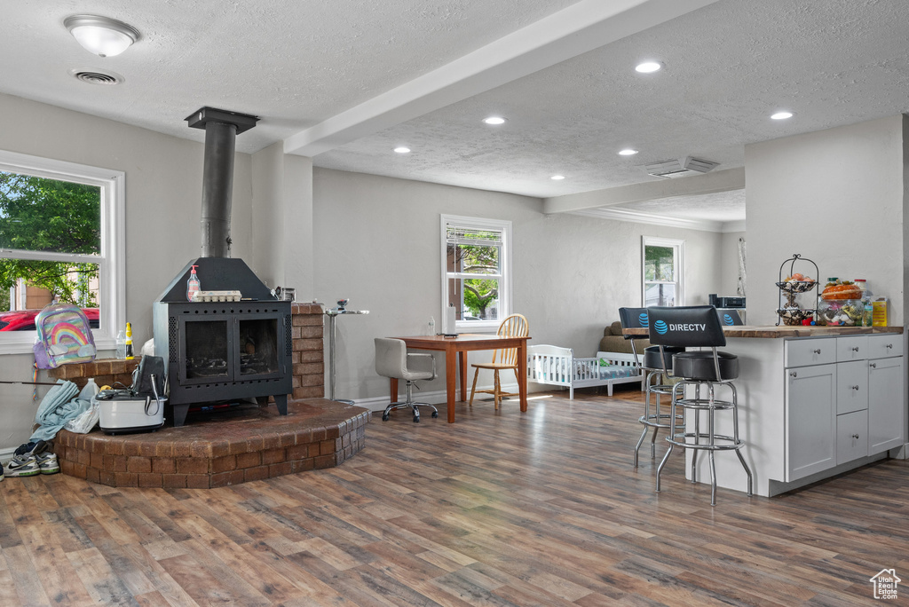 Living area with dark wood-style flooring, a wood stove, a textured ceiling, recessed lighting, and visible vents