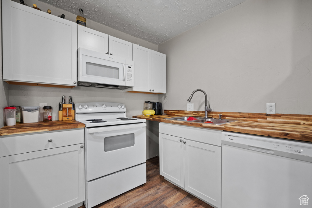Kitchen featuring butcher block countertops, a sink, dark wood-style floors, and white appliances