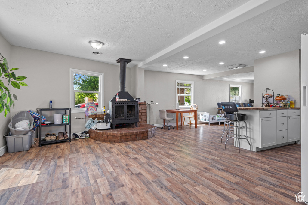 Living room with visible vents, a wood stove, a textured ceiling, and wood finished floors