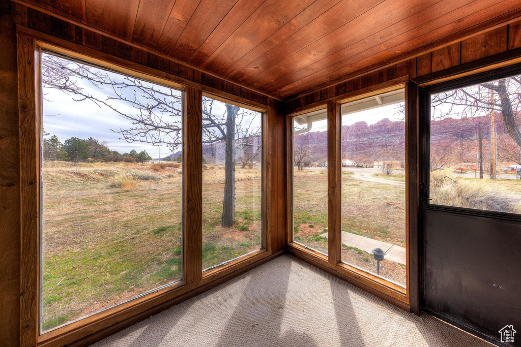 Unfurnished sunroom featuring carpet flooring and wooden ceiling
