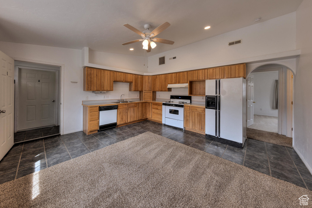 Kitchen featuring visible vents, arched walkways, baseboards, white appliances, and a ceiling fan
