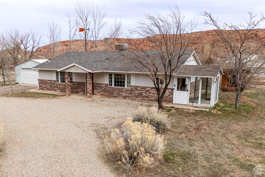 Single story home featuring brick siding, a shingled roof, driveway, a detached garage, and a mountain view