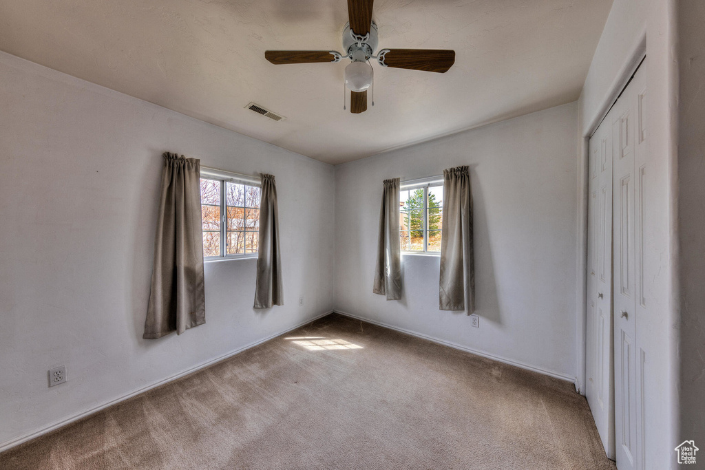 Unfurnished bedroom with a closet, visible vents, multiple windows, and carpet