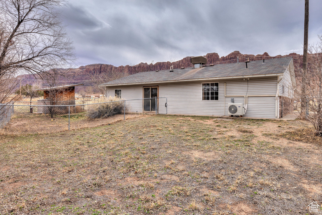 Rear view of house with fence, a lawn, and ac unit