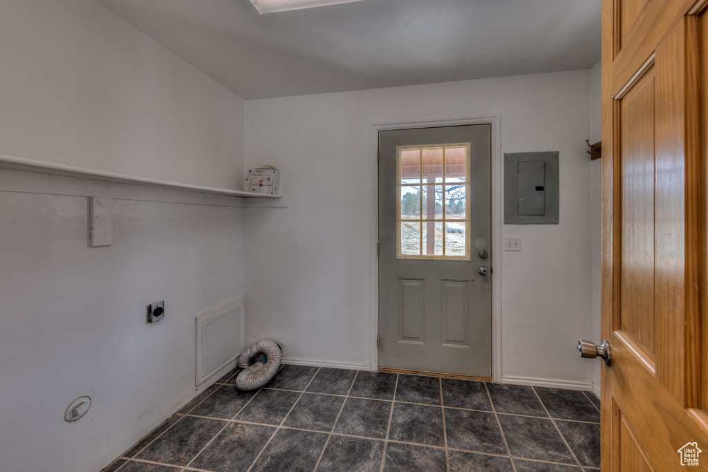 Washroom featuring dark tile patterned floors, electric panel, laundry area, and baseboards
